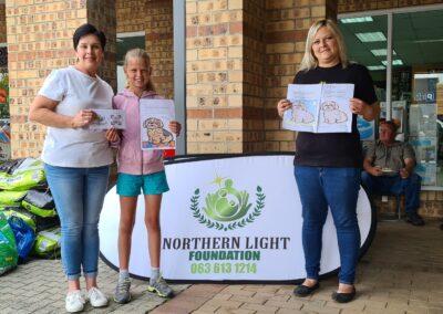 Colouring_Competition__Riana_Labuschagne_Maud_Lottering_Handing_prize_Over_to_Simone_Swart .jpg